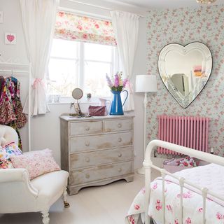 bedroom with pink floral walls and love shaped mirror on wall