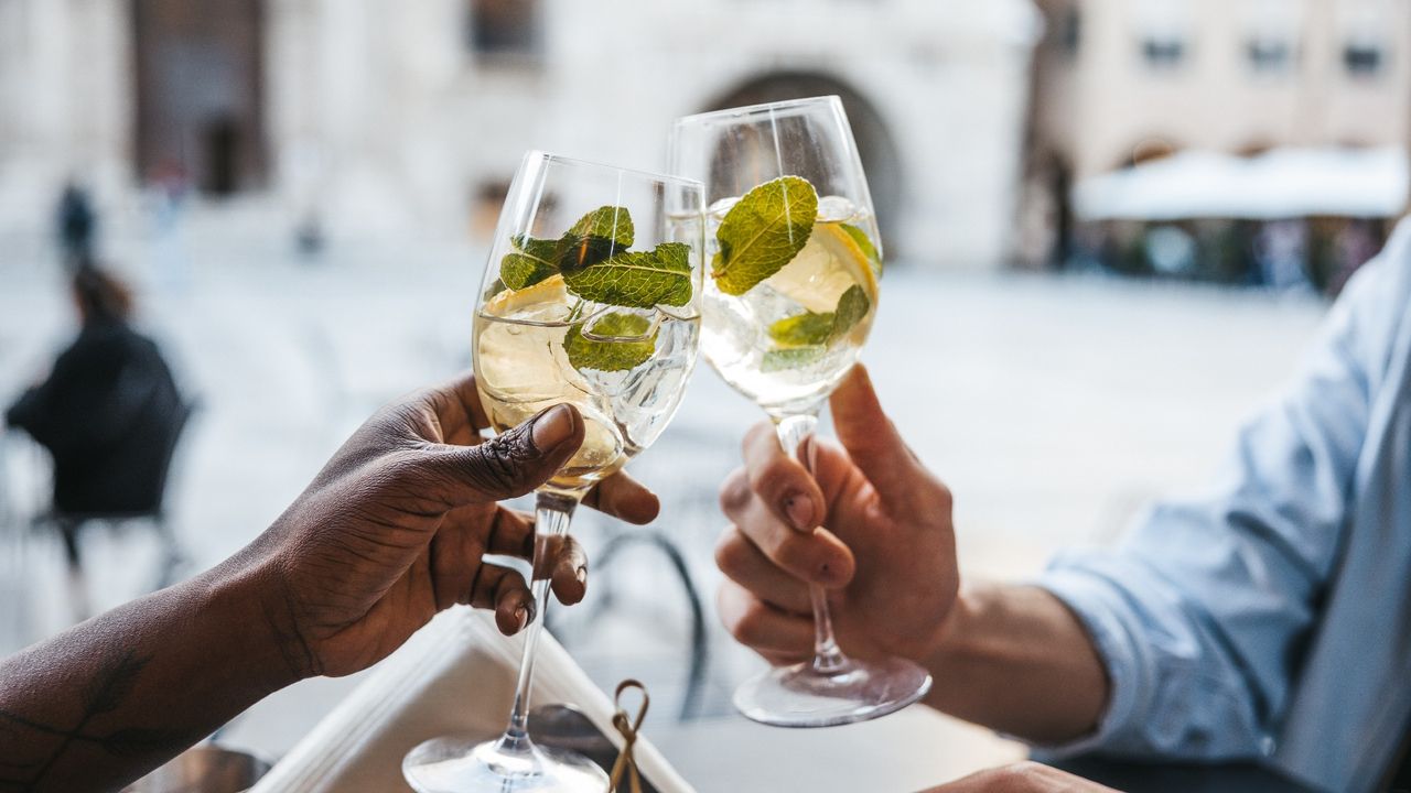 Two people sitting outside clinking glasses of fresh spring cocktails