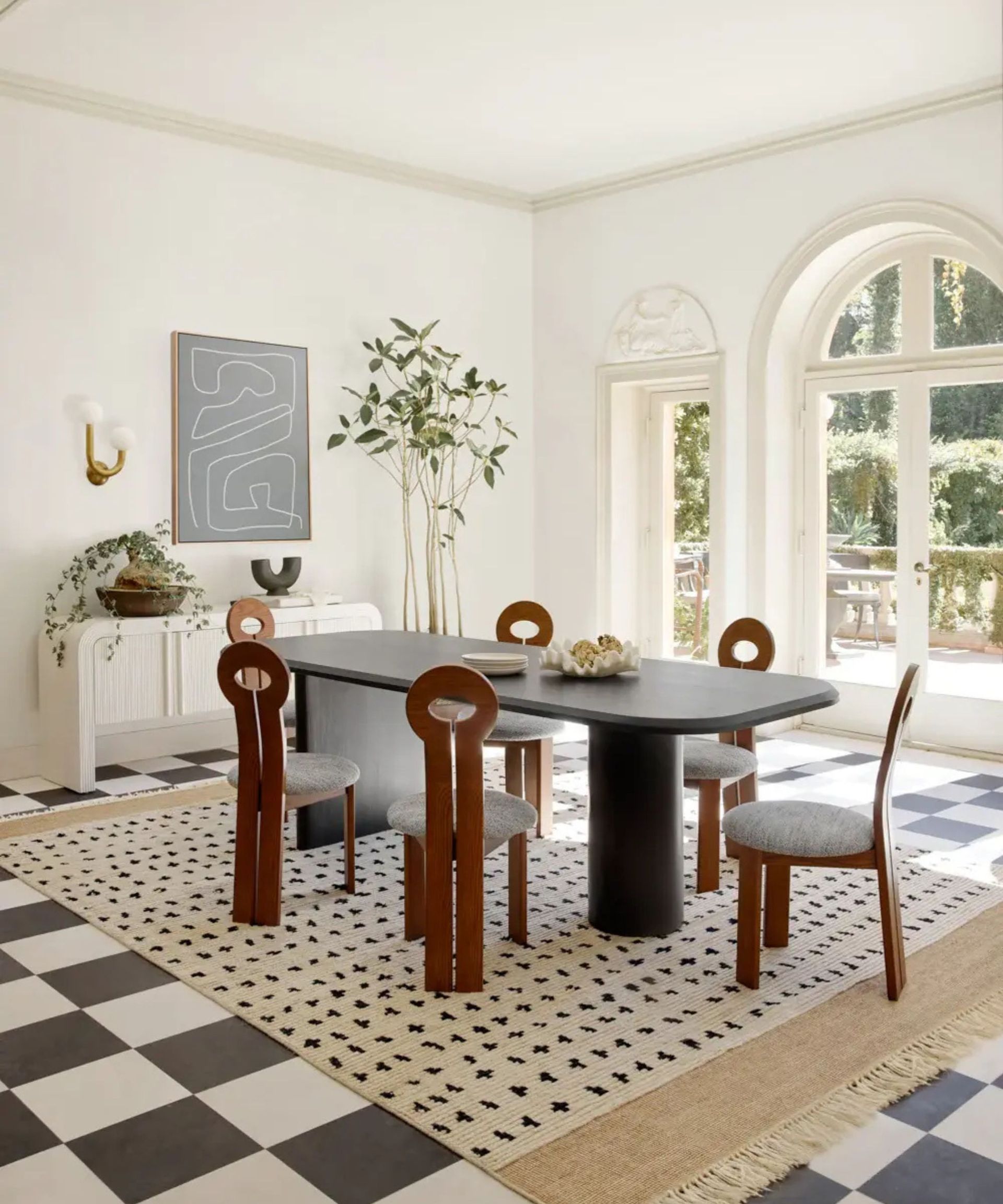 Dining room with arched windows and checkerboard floor with polka dot rug and long black dining table
