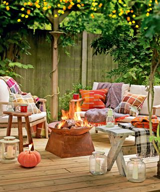 metal fire pit on a deck surrounded by seating, throws and cushions