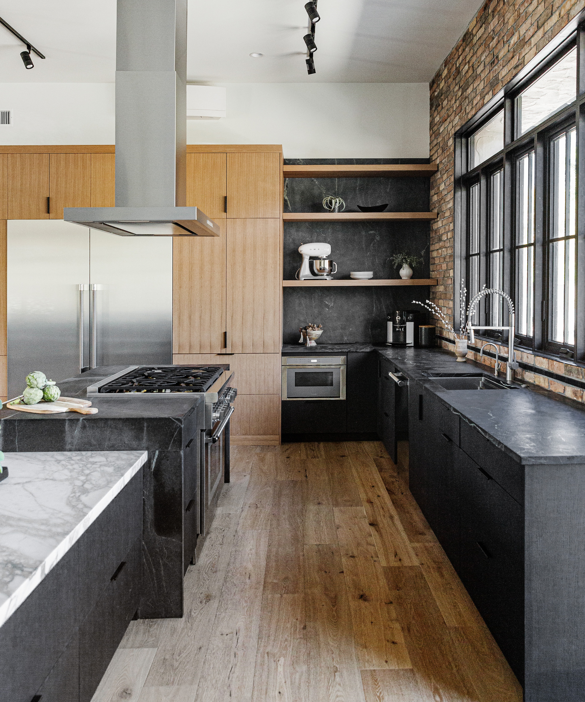 black kitchen with wood floors and steel appliances