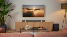 JBL Bar MK2 lifestyle image showing the flagship soundbar beneath a large TV, atop a wooden unit