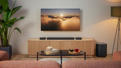JBL Bar MK2 lifestyle image showing the flagship soundbar beneath a large TV, atop a wooden unit