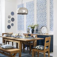 Dining room with wooden furniture and wallpapered wall panels above sideboard