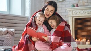 mother reading a book to her daughters 