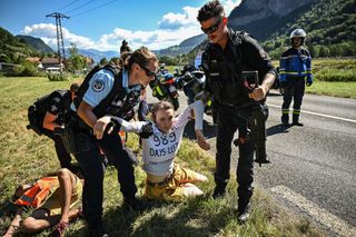 French gendarmes remove environmental protestors from the race route as their protest action temporarily immobilized the pack of riders during the 10th stage of the 109th edition of the Tour de France 