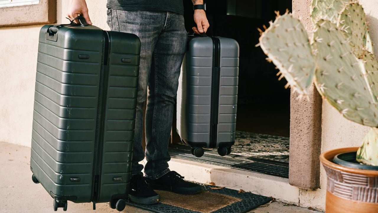 Travel gadgets, person leaving the house carrying two suitcases