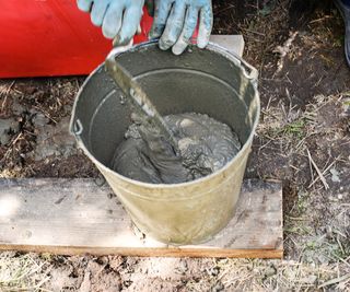 hands mixing mortar in a bucket