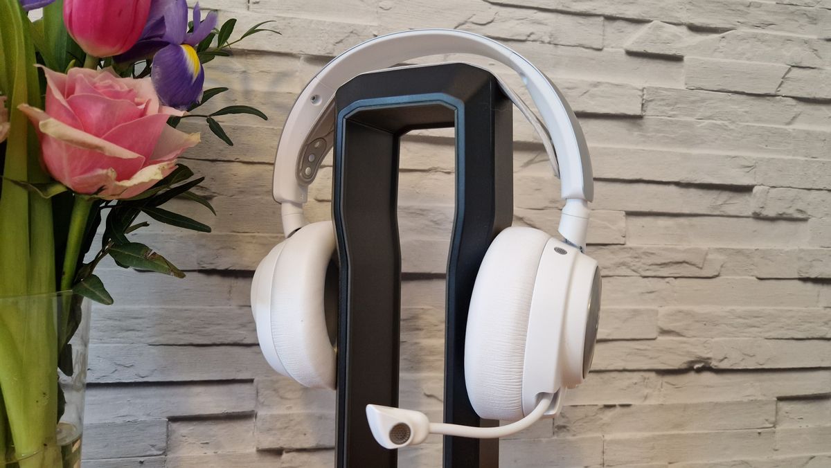 The SteelSeries Arctis Nova Pro Wireless white edition on a headset stand with a white brick background