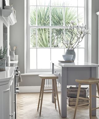 Gray kitchen island near large window in small wooden kitchen