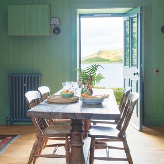 cottage dining room with farmhouse table and wooden chairs and green wood panel walls