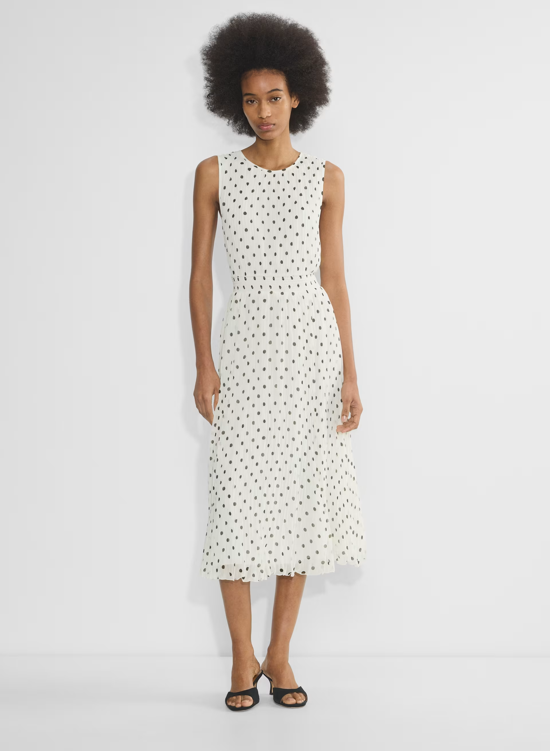 A model wearing a white dress with black polka dots