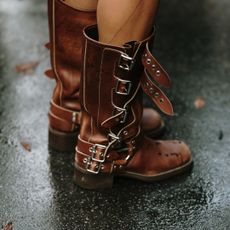 Brown leather moto boots with buckles on black wet pavement 