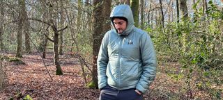 Hiker wearing Helly Hansen Odin Everdown hooded jacket in the woods