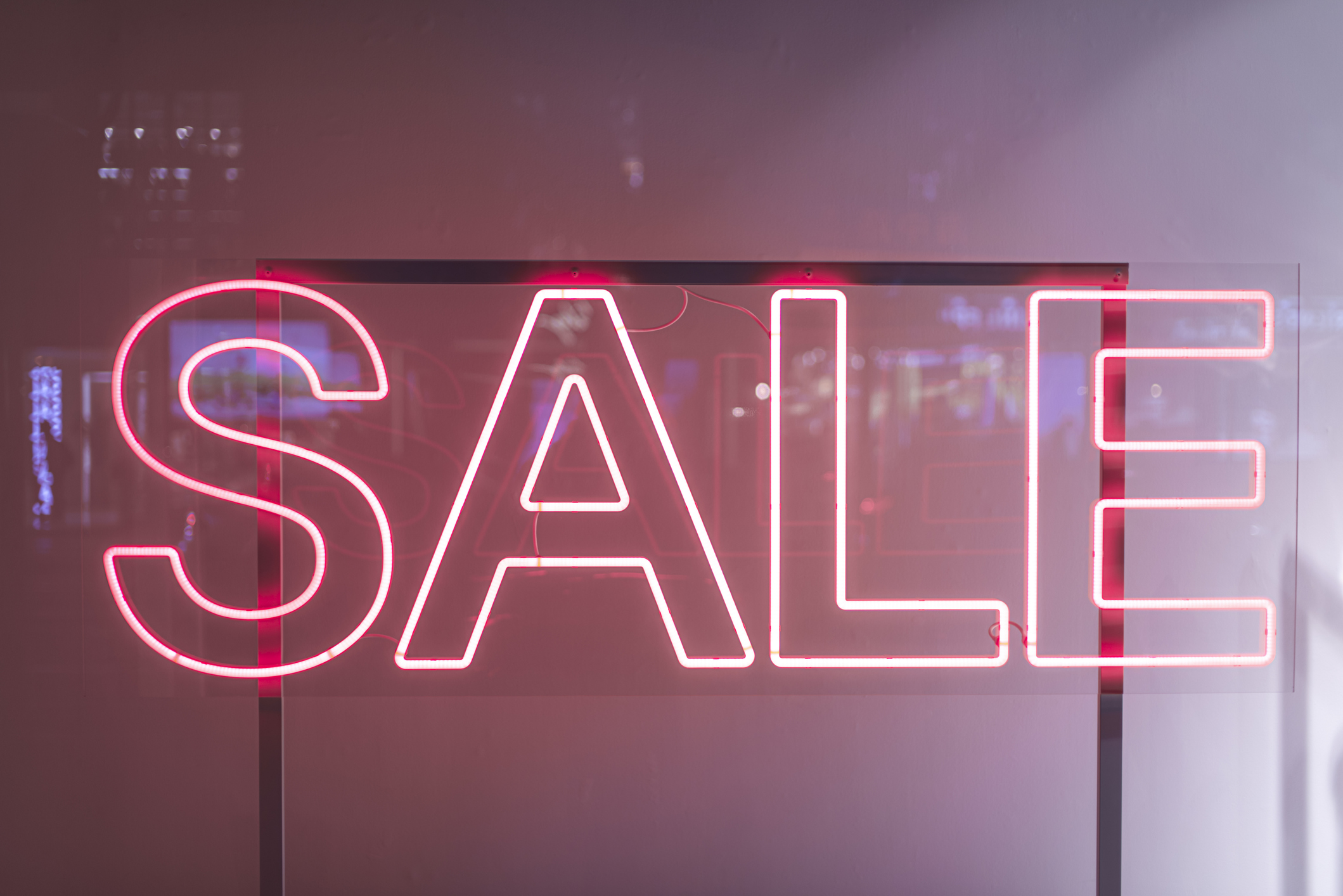 A neon sign that says the word SALE in pink.