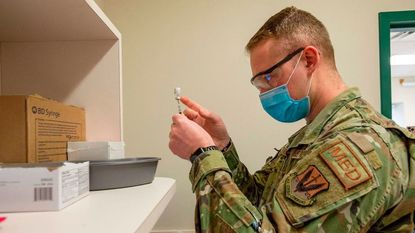An Air Force airman prepares to give a COVID-19 vaccine shot.
