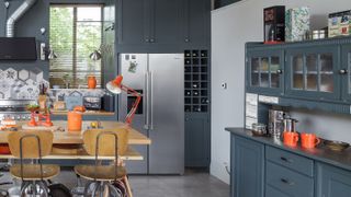dark blue kitchen with large steel fridge and kitchen island
