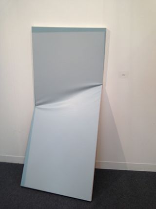 Two pieces of grey material attached to a wall with a diagonal crease in the middle.