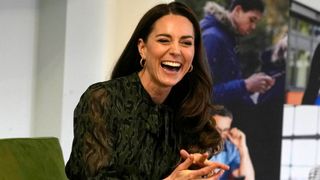 Kate Middleton laughs as she sits on a sofa during her visit to Shout in 2022