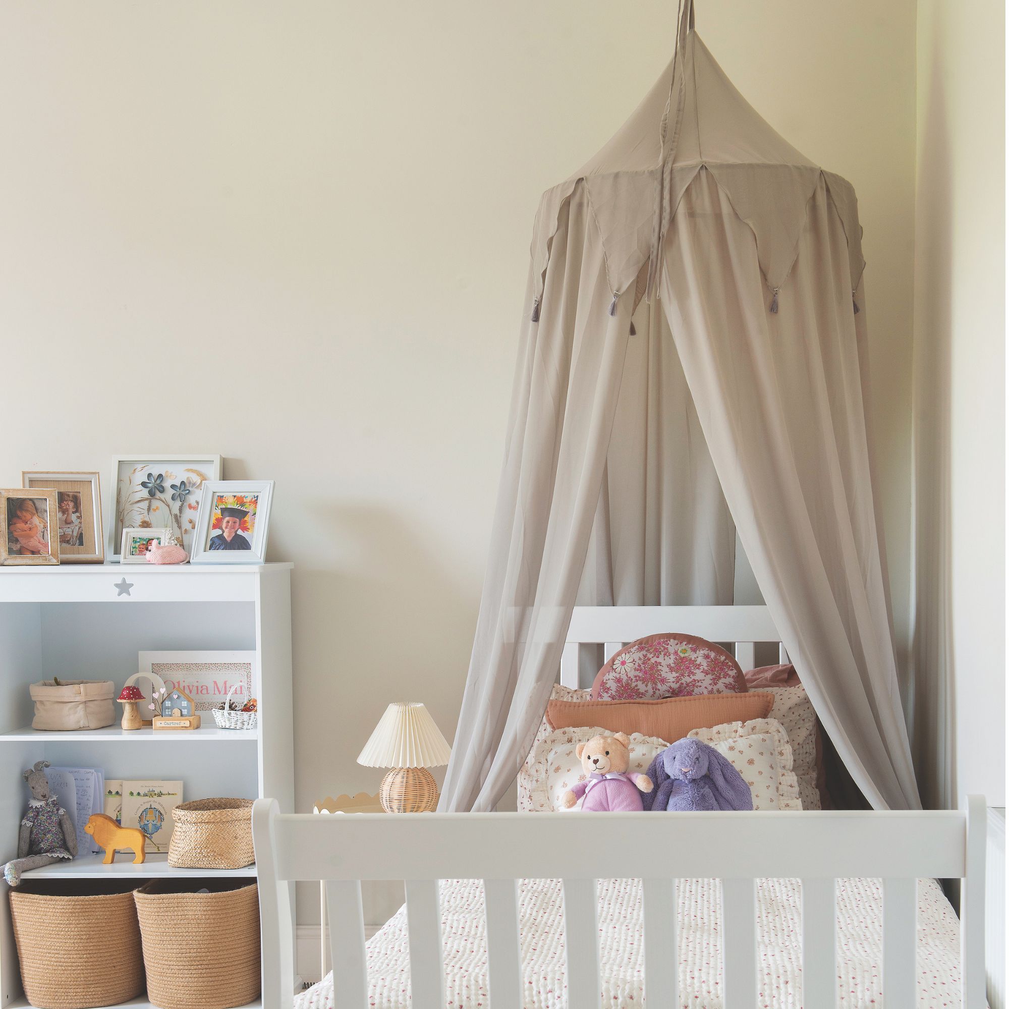 Kids' bedroom in cottage with neutral walls, white slatted bed frame, grey canopy