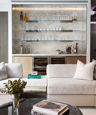 Luxurious bar staged behind cozy white couches with coffee table books on show in the center