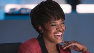 Uhura laughing while playing a game of cards. She's wearing the same classic hairstyle she had in the original series. 