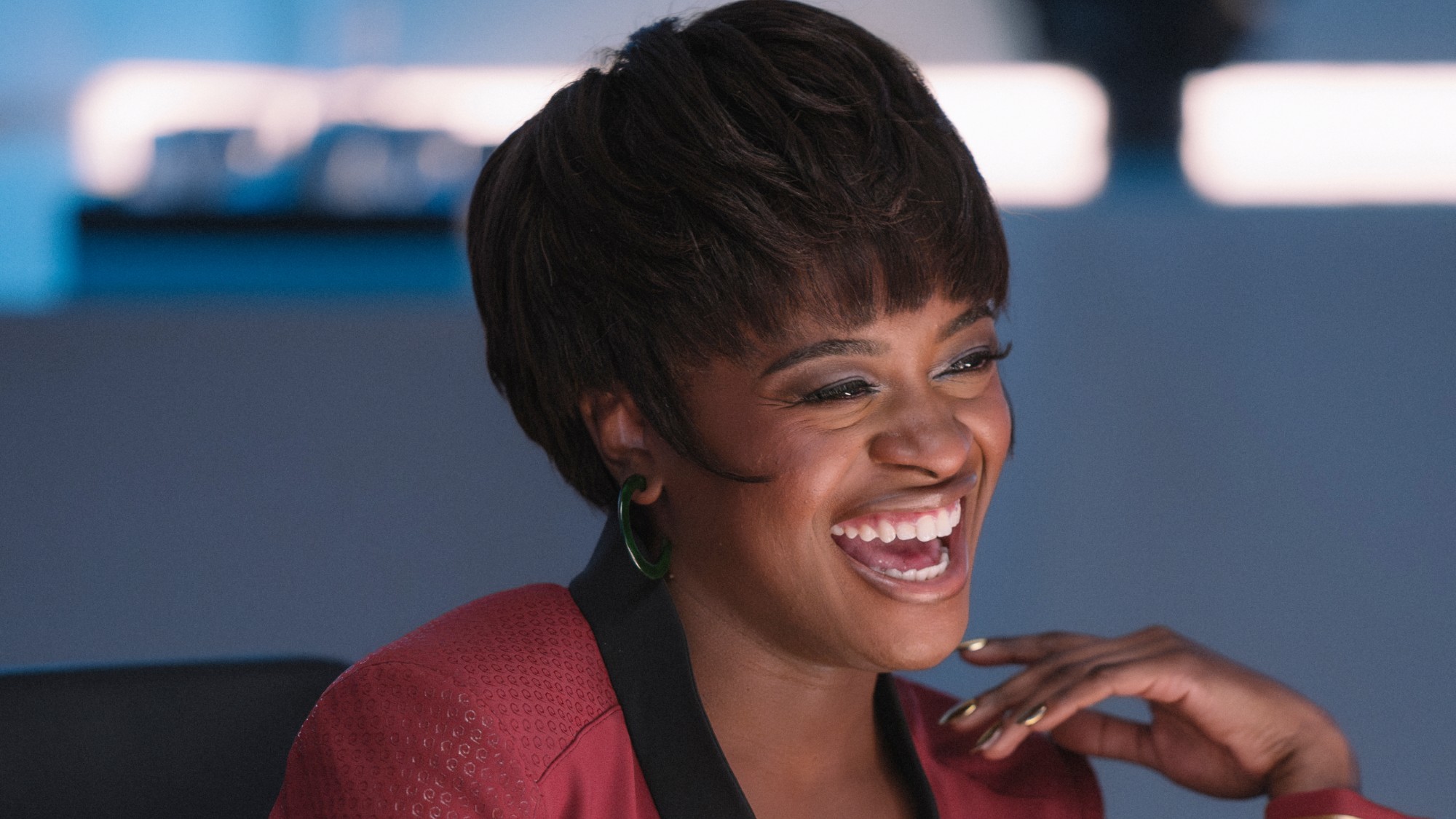 Uhura laughing while playing a game of cards. She's wearing the same classic hairstyle she had in the original series. 