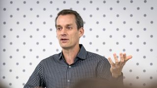 Jeff Dean, chief scientist at Google DeepMind and Google Research, speaking at an event in 2020. He is pictured from the chest up with one hand raised, against a dotted background.