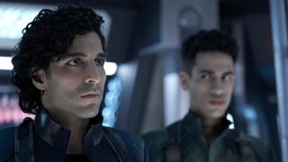 Two dark-haired males from the TV show "The expanse" look worried, one looks forward while one looks at the other