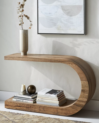 Modern curved console table made of natural wood from Anthropologie.