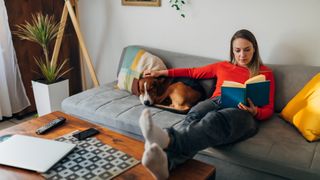 lady sitting on sofa reading with dog