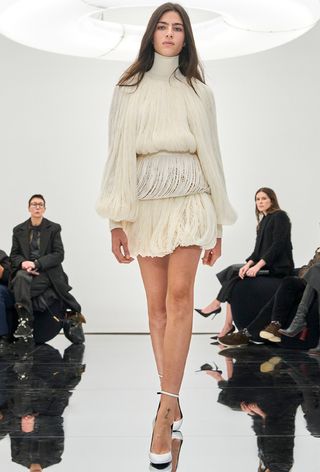 a model on Alaïa's fall runway wearing a bubble hem skirt with matching fringe turtleneck
