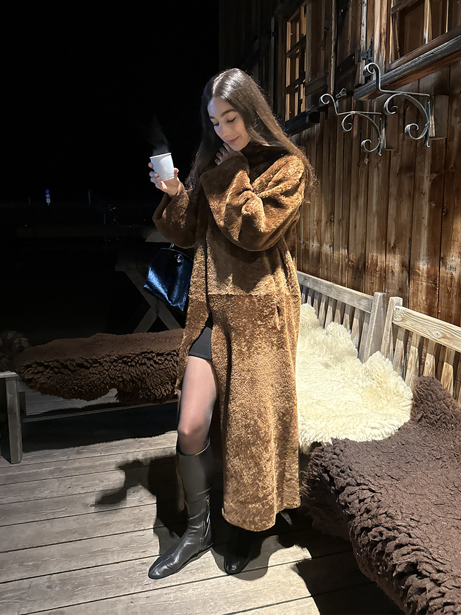 Melanie Masarin Ghia Founder Looking Down Wearing Fur Brown Long Coat and Boots