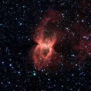 Spitzer Space Telescope image, the two opposing bubbles are being formed in opposite directions by the powerful outflows from massive groups of forming stars. The baby stars can be seen as specks of yellow where the two bubbles overlap.