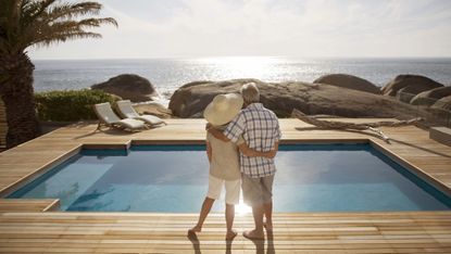 Senior couple by modern pool overlooking ocean