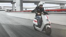 NQi GTS electric scooter in white being ridden by a man in sunglasses on a freeway