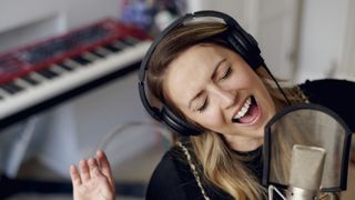 Woman wearing headphones sings into a microphone
