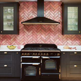 Black kitchen with pink subway tiles in chevron pattern.