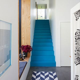 hallway with white walls and blue staircase