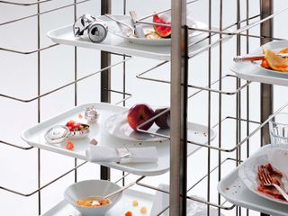 Tableware on trays on rack cluttered with food and drink