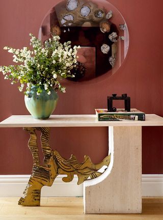 Red hallway with white console and vase of flowers and art on wall