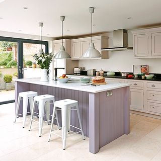 lilac island with netural cabinets and white stools