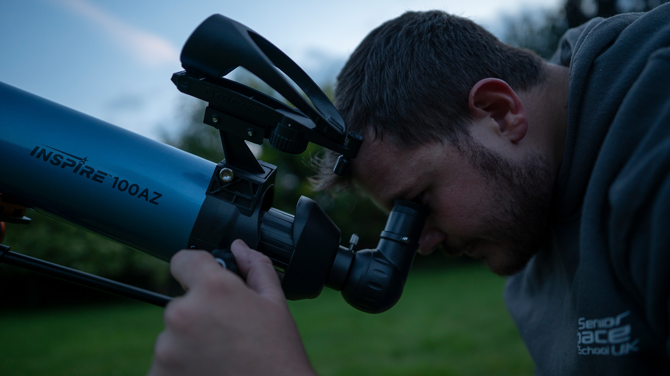 Man looking into a telescope in a field