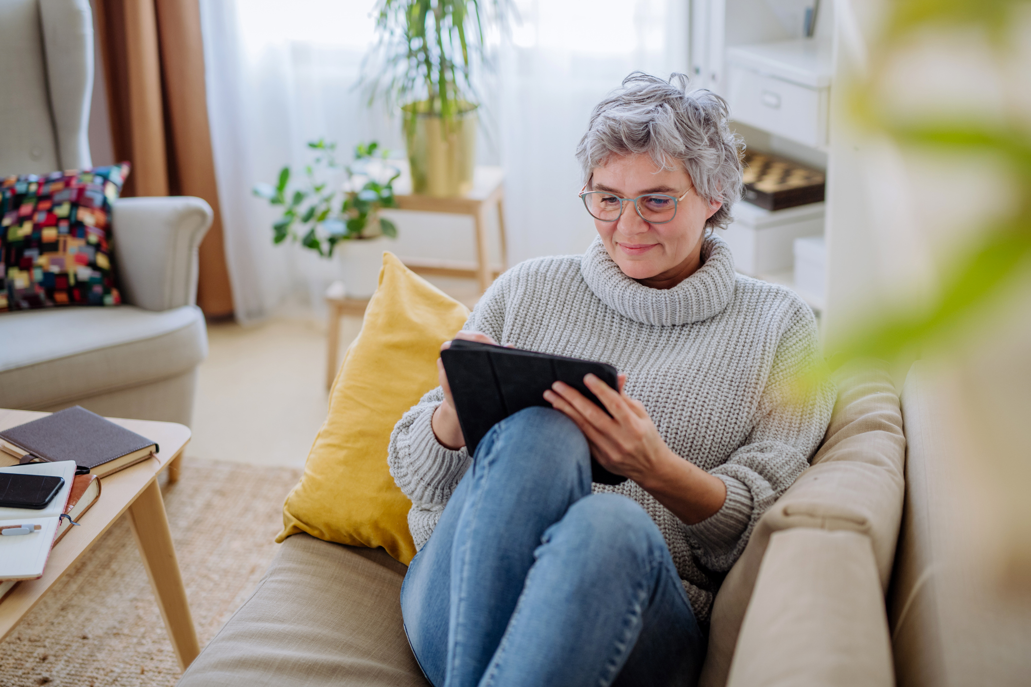 Woman using a tablet while sitting on a sofa at home