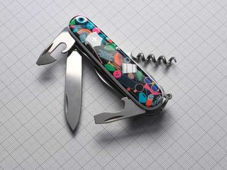 An open Swiss Army knife with a case with multiple colourful art items including a sunglasses, a keyboard, a trumpet, a bat, a rainbow, an eye, a ball, a bug.