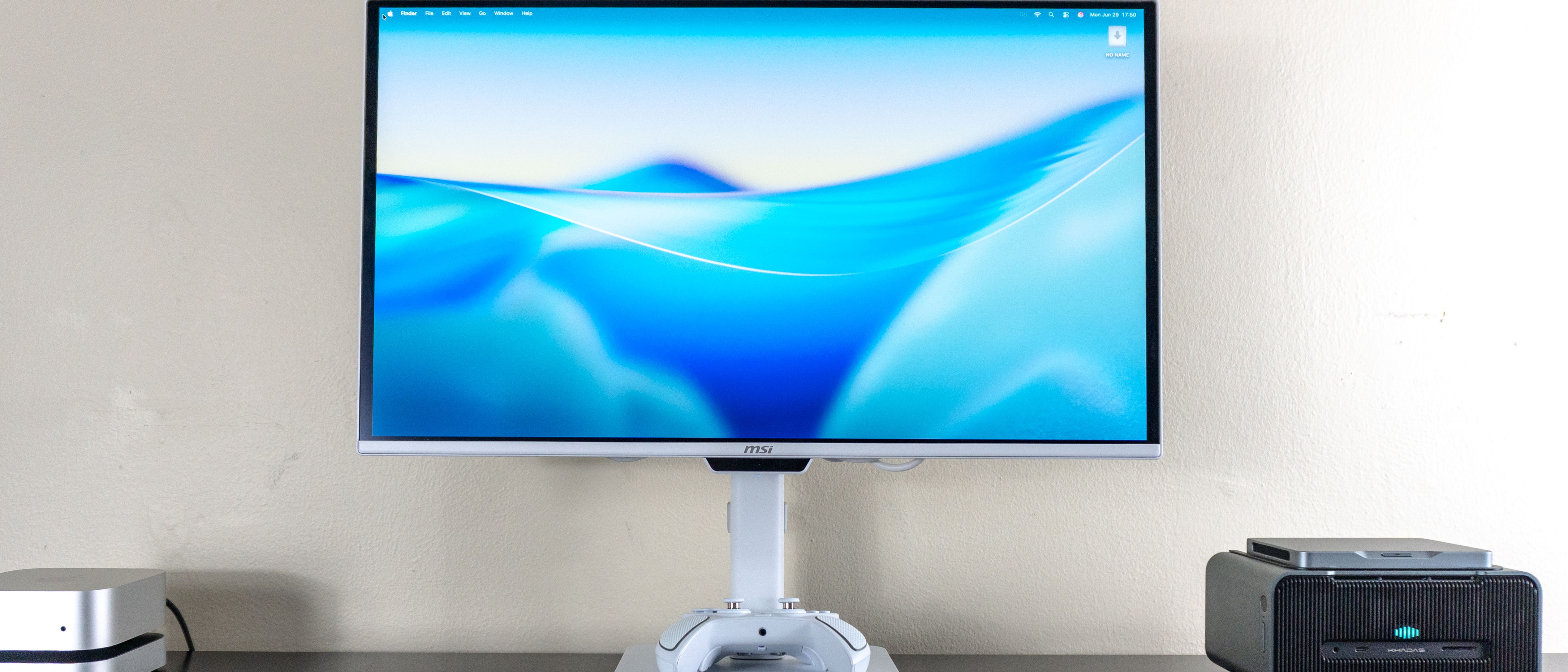 The MSI Pro Max 271UPXW12G monitor on a desk with a Mac mini on one side and a mini PC on the other