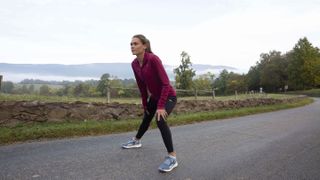 Reebok Boston Track Club pro runner Josette Norris stretching on a country road