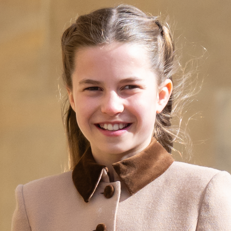 Princess Charlotte wears a light brown coat with a dark collar and smiles