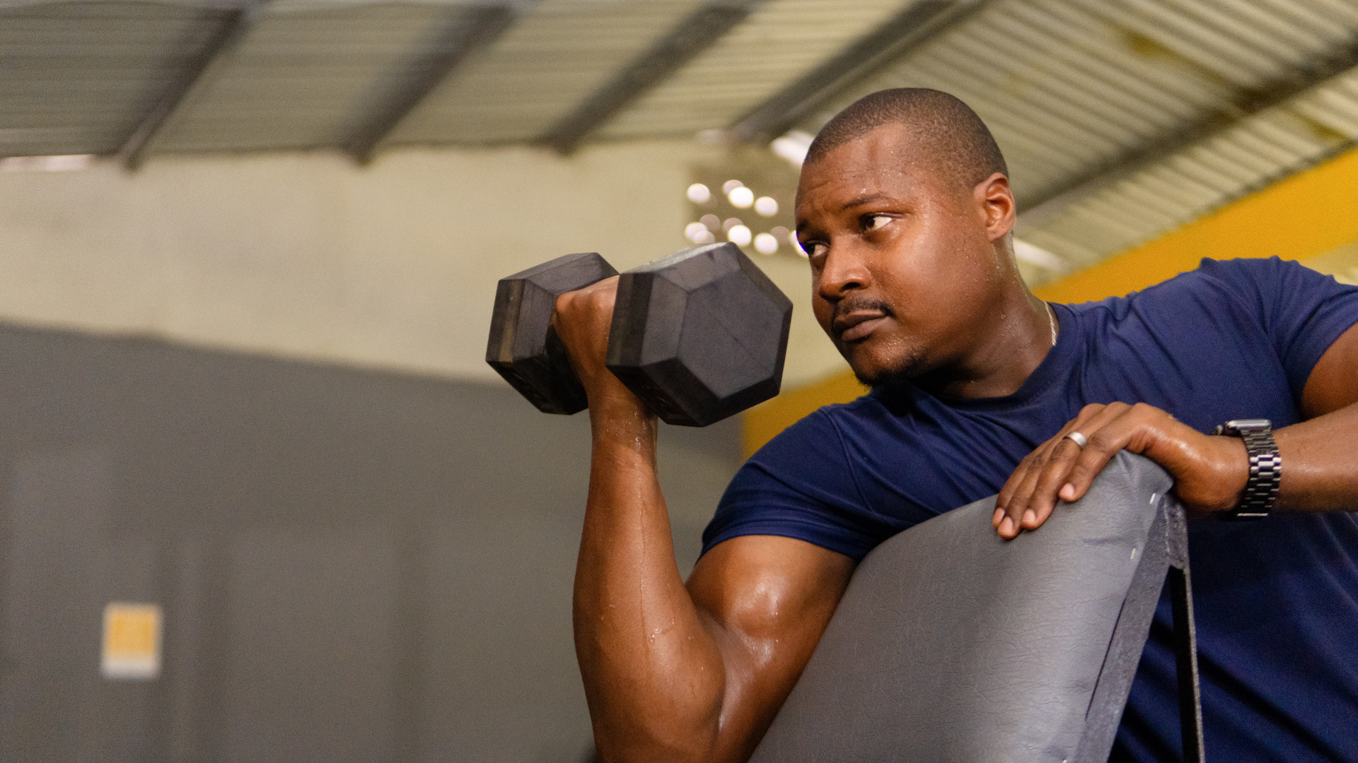A man performing a dumbbell preacher curl
