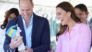 GREAT ABACO, BAHAMAS - MARCH 26: Prince William, Duke of Cambridge and Catherine, Duchess of Cambridge receive a gift during a visit to a Fish Fry – a quintessentially Bahamian culinary gathering place which is found on every island in The Bahamas on March 26, 2022 in Great Abaco, Bahamas. Abaco was dramatically hit by Hurricane Dorian, It damaged 75% of homes across the chain of islands and resulted in tragic loss of life. During their visit to the Church they will hear first-hand what it was like to be on the island at the point the hurricane hit, and how people have come together to support each other during an incredibly difficult time. The Duke and Duchess of Cambridge are visiting Belize, Jamaica and The Bahamas on behalf of Her Majesty The Queen on the occasion of the Platinum Jubilee. The 8 day tour takes place between Saturday 19th March and Saturday 26th March and is their first joint official overseas tour since the onset of COVID-19 in 2020.
